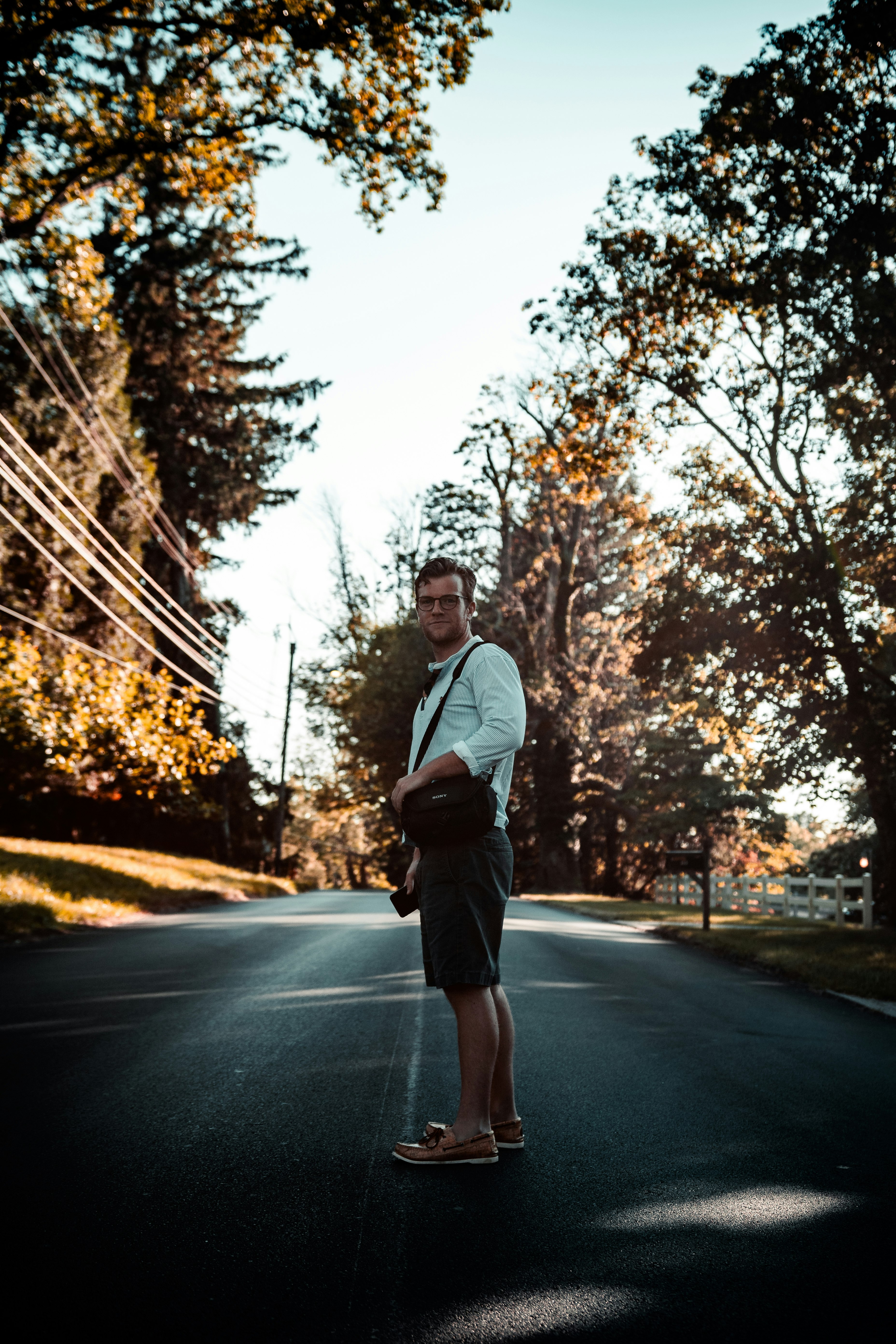 man in gray hoodie standing on road during daytime